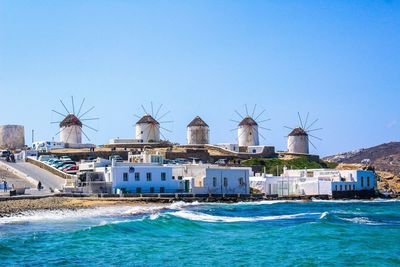 Sea and buildings against clear blue sky