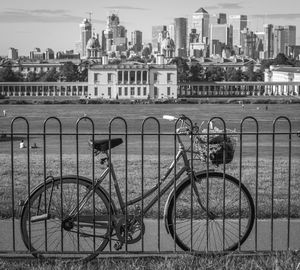 Bicycle on railing by river against buildings in city