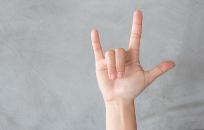 Cropped hand of woman gesturing against wall