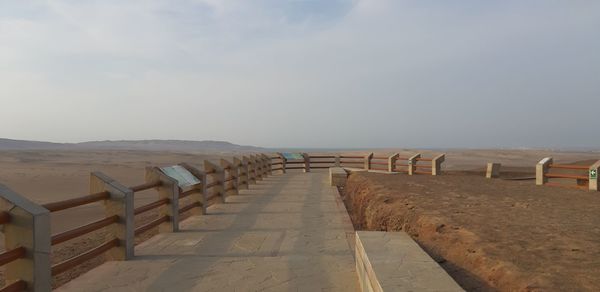 Empty seats on beach against sky