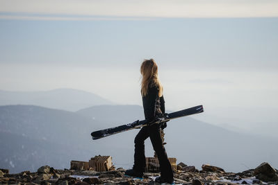Rear view of woman standing on mountain against sky