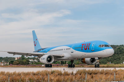 Airplane flying over airport runway against sky