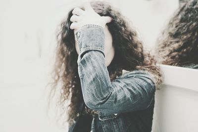 Close-up of woman with hand in hair by mirror