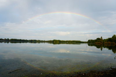 Scenic view of rainbow over lake against sky