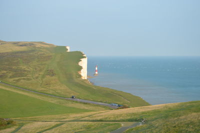Scenic view of sea by cliff against clear sky