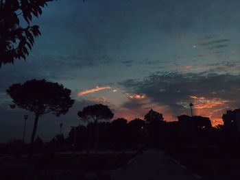 Silhouette trees against dramatic sky during sunset