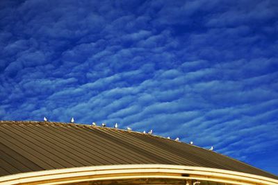 Low angle view of building roof against cloudy sky