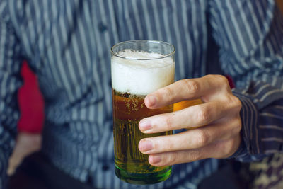 Midsection of man holding beer glass