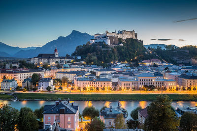 Illuminated buildings in town against sky