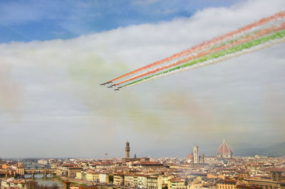 Airplane flying over cityscape against sky