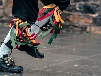 Close-p of a morris dancers legs and feet, showing brightly coloured ribbons, and bells