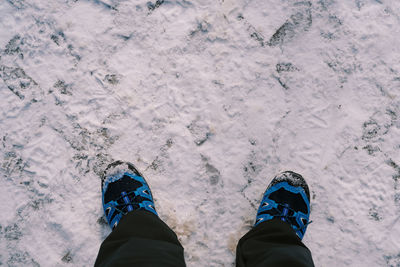 Low section of person standing on snow covered field