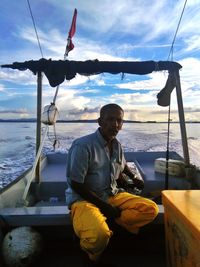 Portrait of fisherman sitting in boat against sky