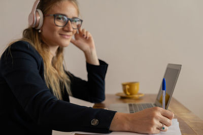 Woman working at home with laptop and papers on desk and headphones. home office . gray notebook 