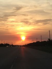 Scenic view of road against cloudy sky during sunset