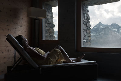 Woman looking thorough window at mountains
