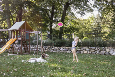 Playful girl throwing frisbee with dog at playground