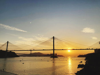 View of suspension bridge over river at sunset