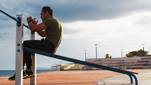 Strong athletic guy doing abs exercises outdoor