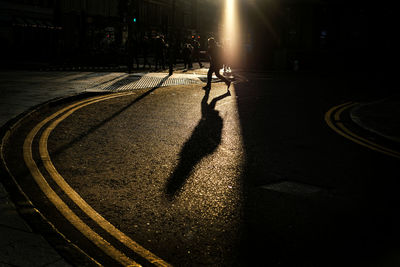 Shadow of person walking on street in city