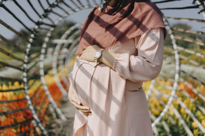Midsection of woman with umbrella standing outdoors
