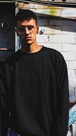 Portrait of young man standing against wall