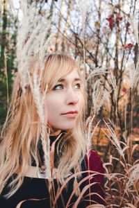 Thoughtful woman standing against plants