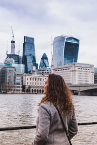 Rear view of mature woman standing against buildings in city