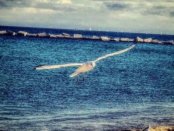 Boats in sea against cloudy sky