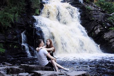 Couple sitting against waterfall