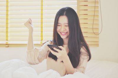 Young woman using mobile phone on bed