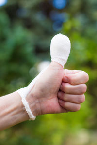 Cropped image of injured hand gesturing thumbs up sign outdoors