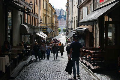 People walking on street amidst buildings in city