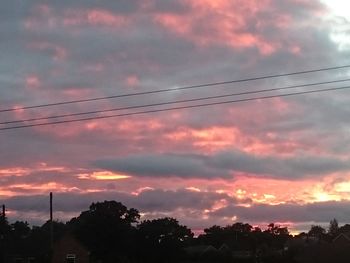 Low angle view of silhouette trees against dramatic sky