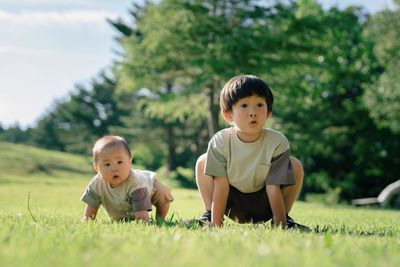 Side view of boy sitting on grassy field