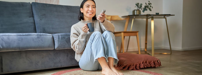 Portrait of young woman sitting on sofa at home