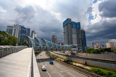 Cars on road by buildings against sky in city