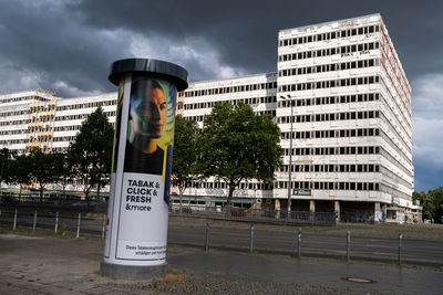 Road sign by building against sky in city