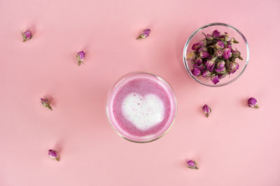 Pink rose milk with rose petals. heart-shaped foam in a glass of moon milk. healthy drink. top view.