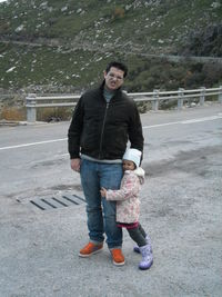 Full length portrait of smiling man standing on road