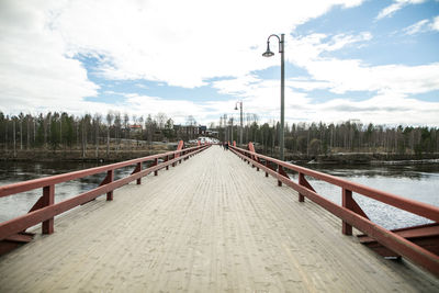 Footbridge over lake against sky