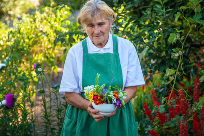 Smiling senior warmer holding flower plants