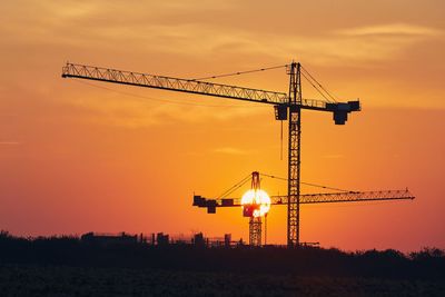 Building activity on contruction site. silhouettes of cranes against sun.