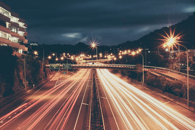 Light trails on road against sky at night