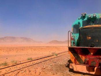 Train on railroad track in desert against sky