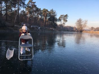 Girl holding chair while standing on frozen lake