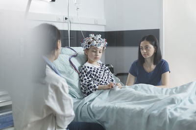 Doctor and visitor sitting with patient in clinic