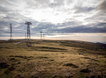 Electricity pylon on field against sky