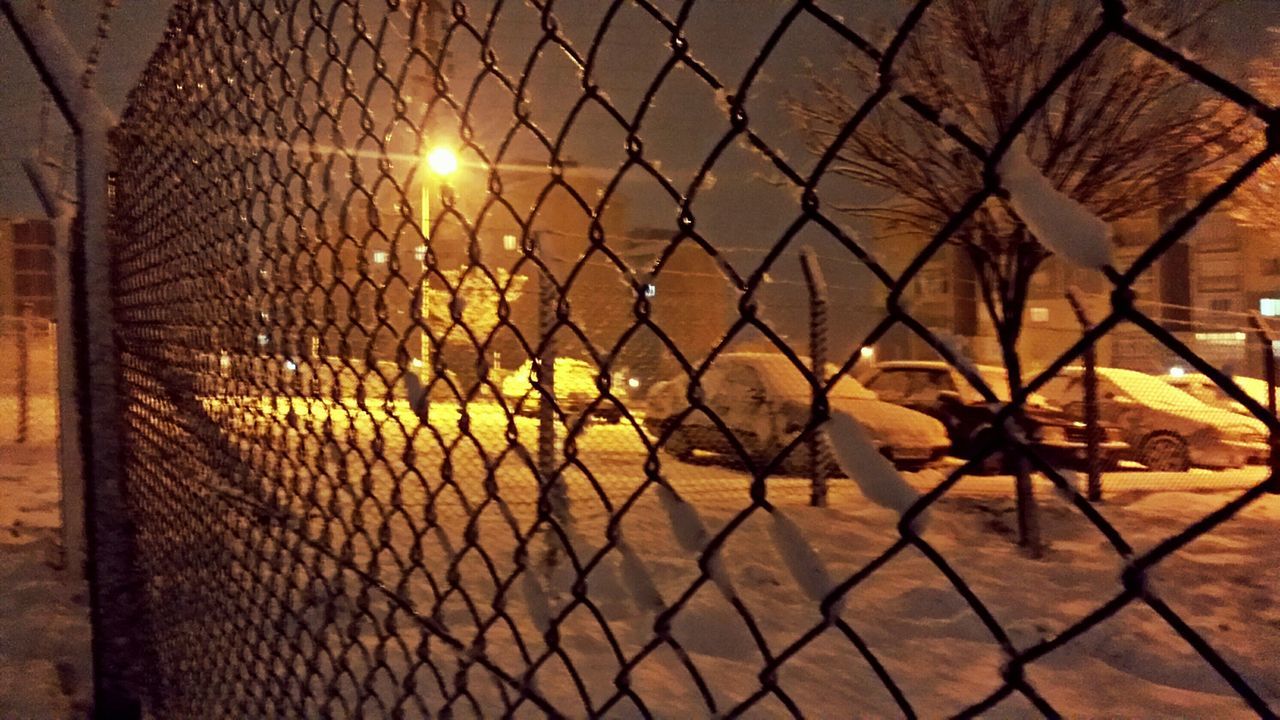 fence, chainlink fence, safety, protection, metal grate, metal, illuminated, built structure, security, architecture, night, pattern, building exterior, gate, sunlight, no people, indoors, wall - building feature, window, closed