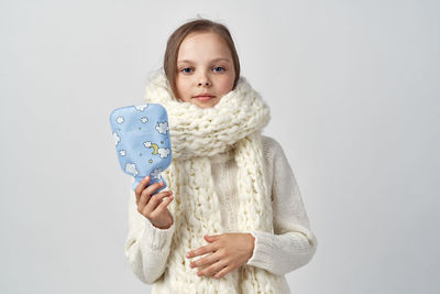 Portrait of smiling young woman using mobile phone against white background